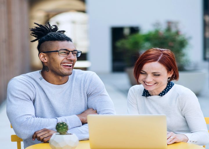 Two colleagues laughing at a laptop